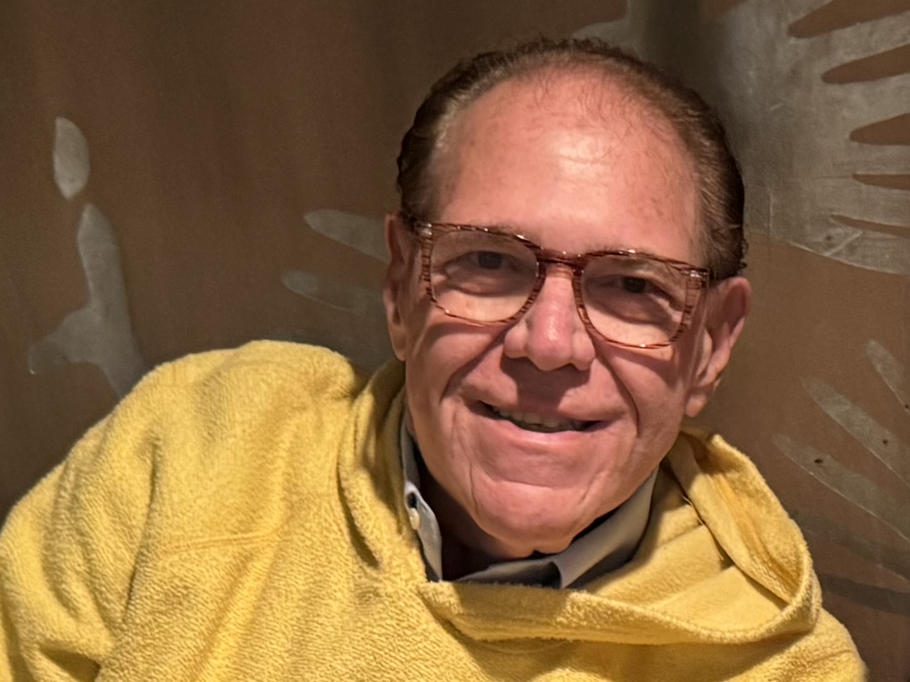 Jerry Perone smiling in a yellow sweater.